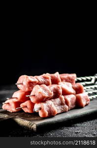 Fresh raw pork kebab on a cutting board. On a black background. High quality photo. Fresh raw pork kebab on a cutting board.