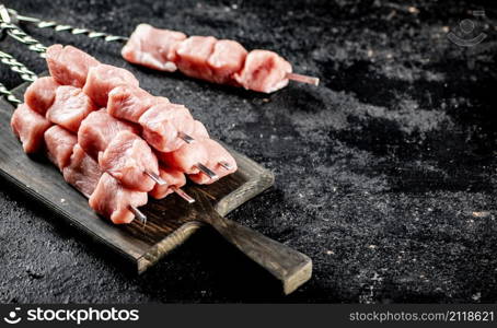 Fresh raw pork kebab on a cutting board. On a black background. High quality photo. Fresh raw pork kebab on a cutting board.