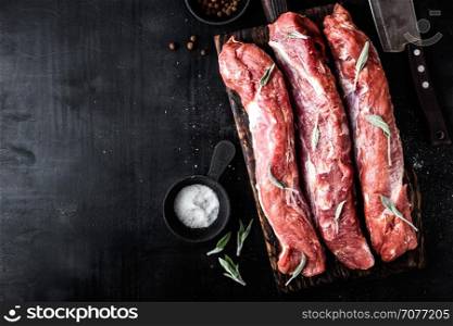 fresh raw pork tenderloin on wooden cutting board on dark background. fresh raw pork tenderloin on wooden cutting board on dark background and blank space for your text