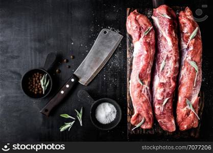 fresh raw pork tenderloin on wooden cutting board on dark background. fresh raw pork tenderloin on wooden cutting board on dark background and blank space for your text