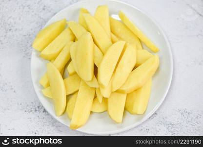 fresh raw potato wedges, chopped potatoes for cooked food on white plate