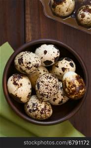 Fresh raw quail eggs in rustic bowl, photographed overhead with natural light (Selective Focus, Focus on the top of the eggs on the top)
