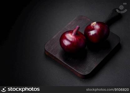 Fresh raw red onion on dark textured concrete background. Cooking at home