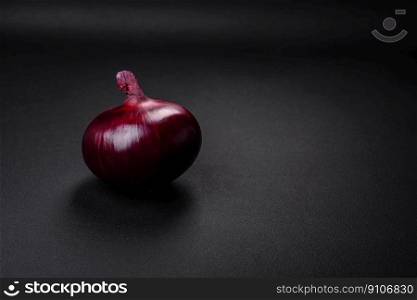 Fresh raw red onion on dark textured concrete background. Cooking at home