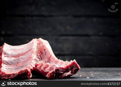 Fresh raw ribs on the table. Against a dark background. High quality photo. Fresh raw ribs on the table.