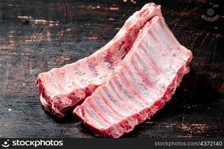 Fresh raw ribs on the table. Against a dark background. High quality photo. Fresh raw ribs on the table.