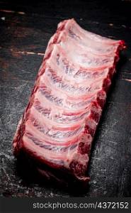 Fresh raw ribs on the table. On a rustic dark background. High quality photo. Fresh raw ribs on the table.