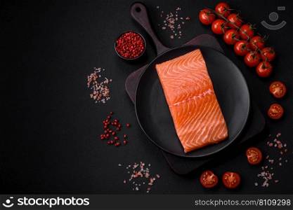 Fresh raw salmon red fish fillet with salt and spices on a dark concrete background