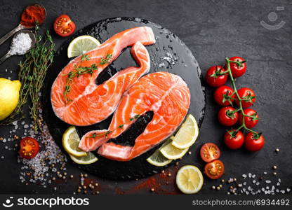 Fresh raw salmon red fish steaks on black background, top view