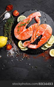 Fresh raw salmon red fish steaks on black background. Top view. Fresh raw salmon red fish steaks on black background, top view
