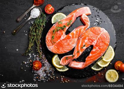 Fresh raw salmon red fish steaks on black background. Top view. Fresh raw salmon red fish steaks on black background, top view
