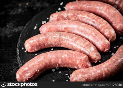 Fresh raw sausages for frying. On a black background. High quality photo. Fresh raw sausages for frying.