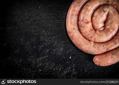 Fresh raw sausages for frying. On a black background. High quality photo. Fresh raw sausages for frying.