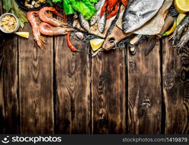 Fresh raw seafood. A variety of seafood on a fishing net. On wooden background.. variety of seafood on a fishing net.