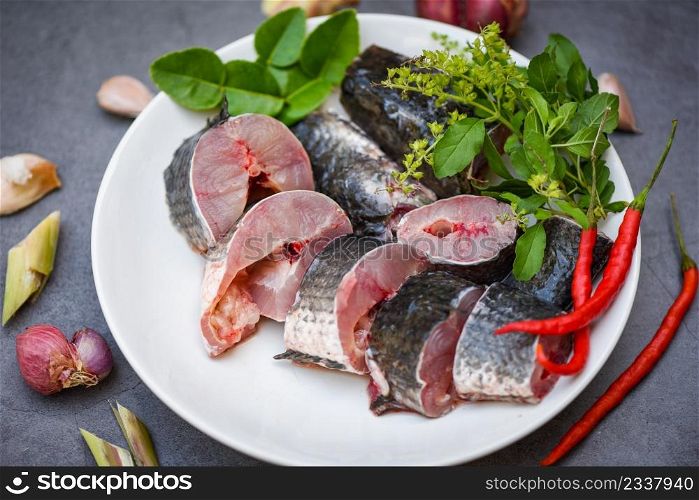 Fresh raw Snake head fish menu freshwater fish, Snakehead fish for cooking food, striped snakehead fish chopped with ingredients herb and spices on white plate and table kitchen background