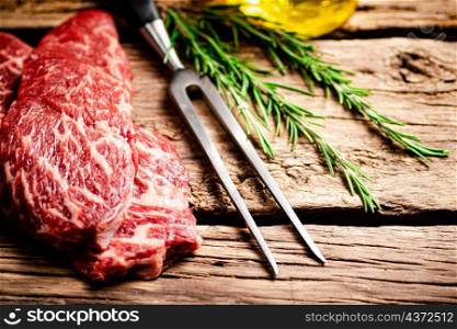 Fresh raw steak with fork. On a wooden background. High quality photo. Fresh raw steak with fork.