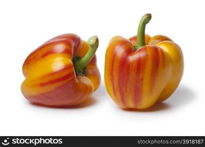 Fresh raw striped yellow and red peppers on white background