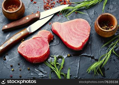 Fresh raw tuna steak and tarragon on kitchen table. Raw tuna steak