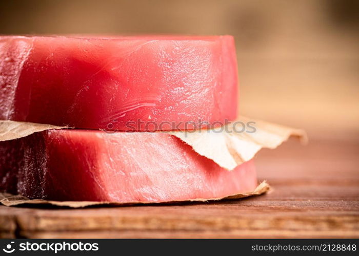 Fresh raw tuna steak on the table. On a wooden background. High quality photo. Fresh raw tuna steak on the table.