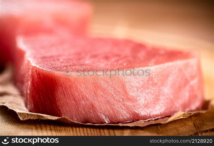 Fresh raw tuna steak on the table. On a wooden background. High quality photo. Fresh raw tuna steak on the table.