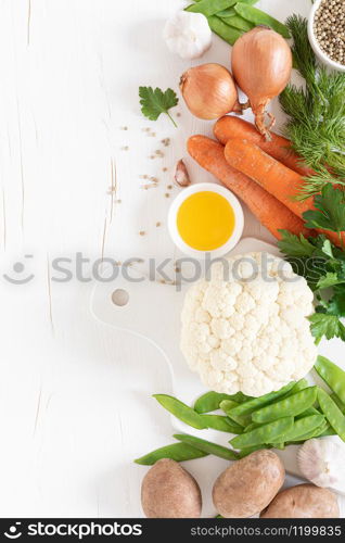 Fresh raw vegetables on white kitchen table, culinary background, top view