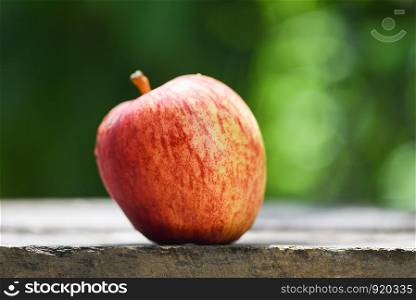 Fresh red apple on wooden table and nature green background in the summer fruit