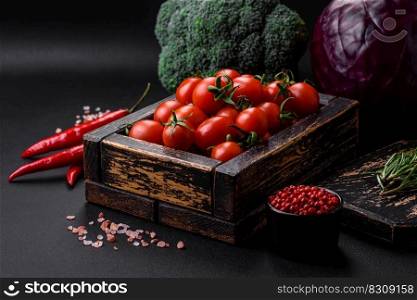 Fresh red cherry tomatoes in a wooden vintage box on a dark concrete background