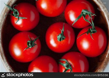 Fresh red cherry tomatoes in wooden bowl. Close-up, top view. Macro, flat lay. Horizontal.