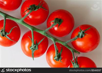 Fresh red cherry tomatoes on twig on white background. Macro, flat lay. Horizontal. Can be used in vertical format.