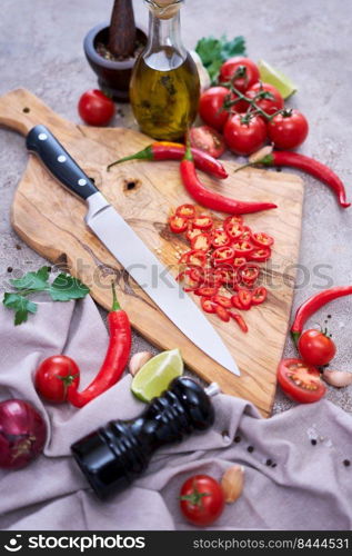 Fresh red chili peppers round slices on wooden cutting board at domestic kitchen.. Fresh red chili peppers round slices on wooden cutting board at domestic kitchen