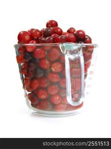 Fresh red cranberries in a glass measuring cup on white background