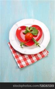 Fresh red delicious tomatoes in plate on an wooden table
