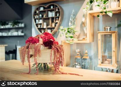 Fresh red flower bouquet with decoration on the table in shop, nobody. Floral composition in boutique, professional floristic service