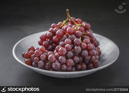 fresh red grape in nice metal plate on dark gray, grey, black tone texture background