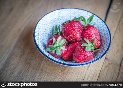 Fresh red organic strawberries in a carboard box on a wooden table