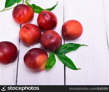Fresh red peaches on a white wooden background, top view