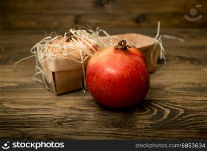 Fresh red pomegranate lying on wooden boards next to basket