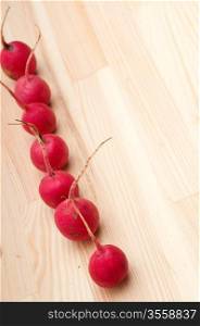 fresh red raw raddish over pine wood table closeup