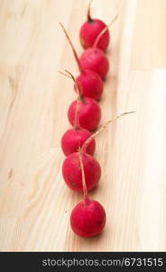 fresh red raw raddish over pine wood table closeup