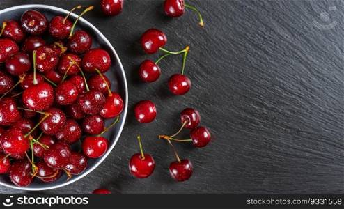 Fresh red ripe sweet cherry with water drops on plate on black slate, stone background. Berry, food background. Top view, banner, header with copy space.. Fresh red ripe sweet cherry with water drops on plate on black slate background.
