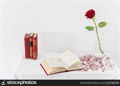 fresh red rose vase near opened book table
