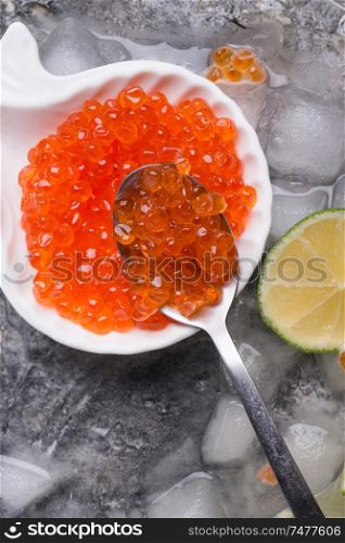 fresh red salmon caviar in spoon. served with lime around ice. macro shot. Protein luxury delicacy healthy food