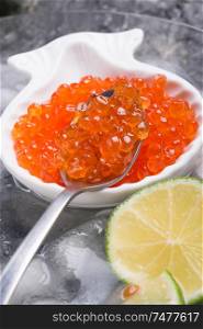 fresh red salmon caviar in spoon. served with lime around ice. macro shot. Protein luxury delicacy healthy food