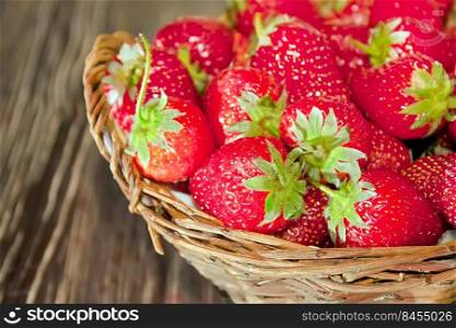 Fresh red strawberries in wicker basket on old brown wooden background. Fresh strawberries on old wooden background