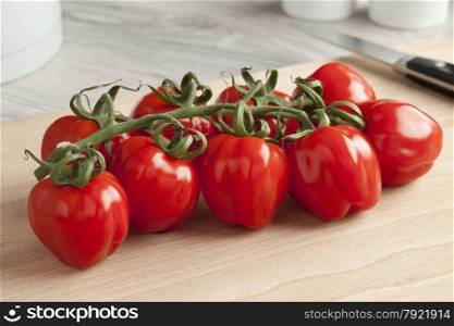 Fresh red tomatoes on a vine on a cutting board