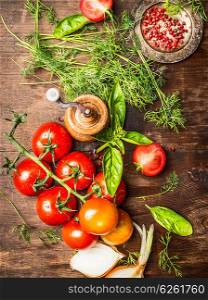 Fresh red tomatoes with green seasoning for tasty sauce cooking. Vegetarian cooking ingredients on rustic wooden background, top view