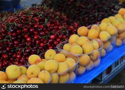 Fresh ripe apricots and cherries lie on counter