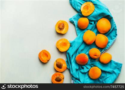 Fresh ripe apricots strew on blue napkin at light mint background, top view Seasonal fruits harvest. Healthy clean eating concept
