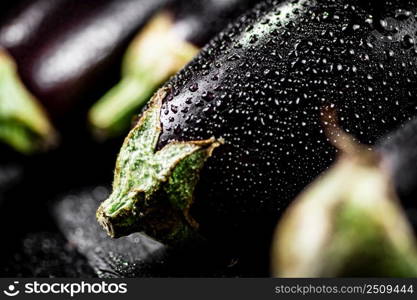 Fresh ripe eggplant with droplets of water on a stone board. On a black background. High quality photo. Fresh ripe eggplant with droplets of water on a stone board. 