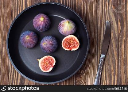 Fresh ripe figs in a dark pan on a wooden table. Healthy Mediterranean figs, selective focus.. Fresh ripe figs in a dark pan on a wooden table. Healthy Mediterranean figs, selective focus
